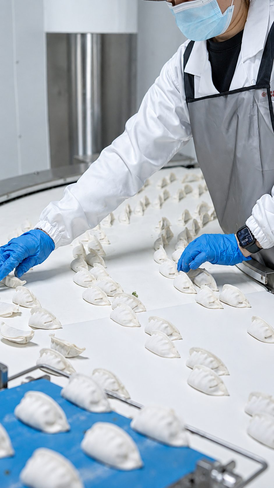 Worker hand-arranging dumplings on the line
